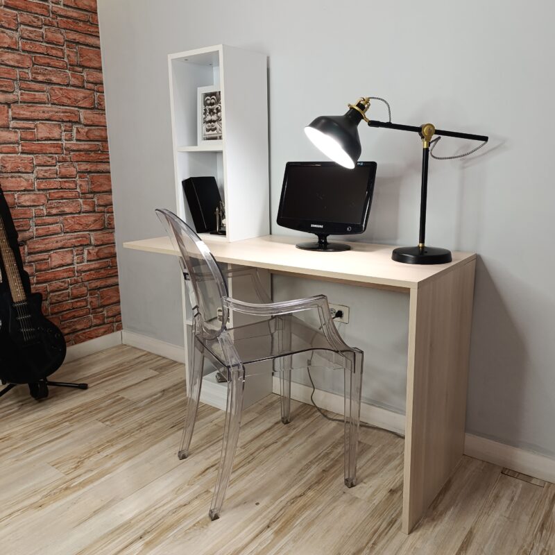 Oficina en casa moderna y minimalista con escritorio de madera, silla acrílica transparente, computadora de escritorio, lámpara negra con detalles dorados, estantería blanca con decoraciones